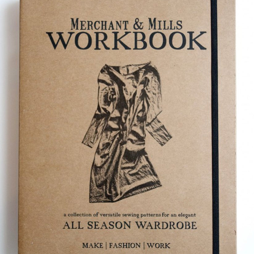 portrait image. white background. book laid flat, book is eco brown, text is black, merchant and mills workbook, all season wardrobe, make fashion work.